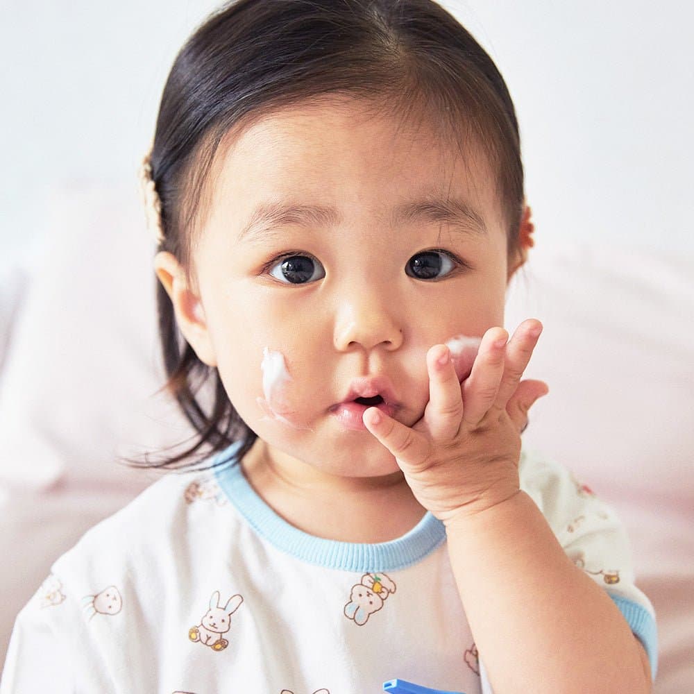 Baby with Cha&Mom Phyto Seline Moisture Lotion on cheek during skincare routine